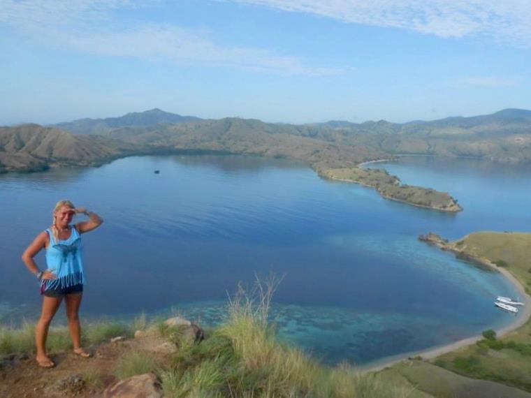 Girl on hill overlooking bay with white boats
