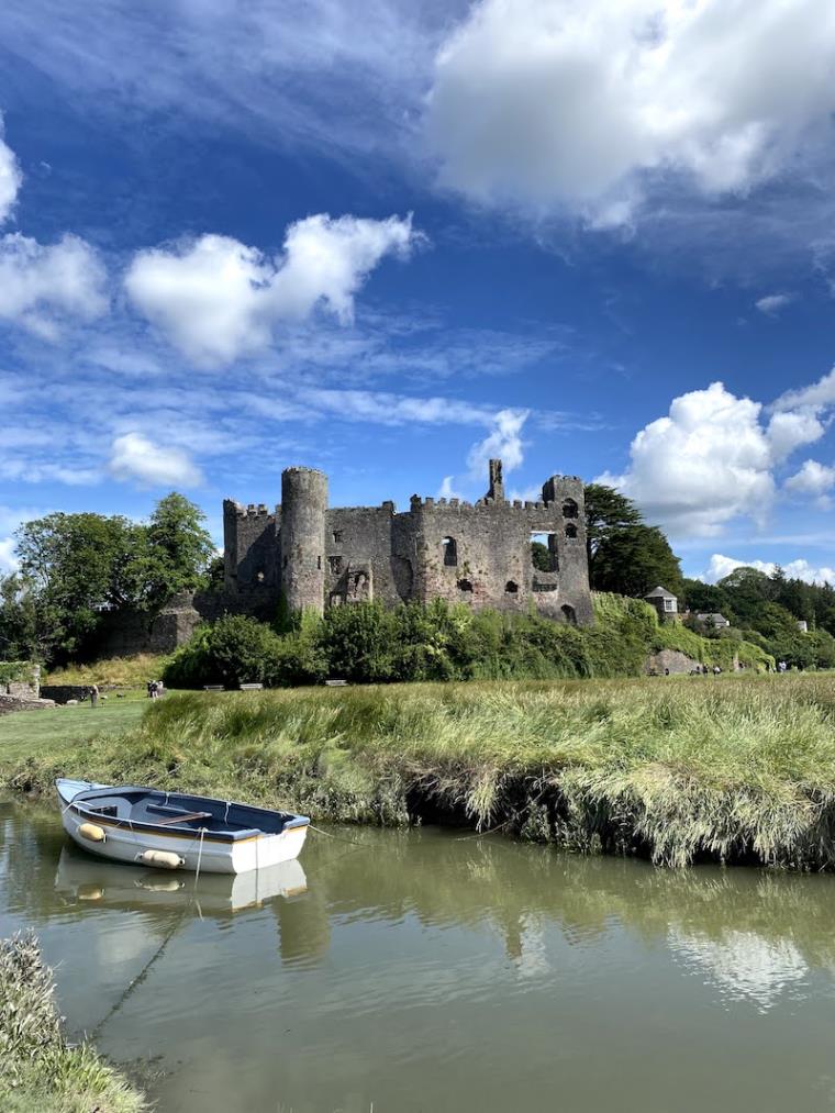 Castle and boat on river in Laugharne Wales